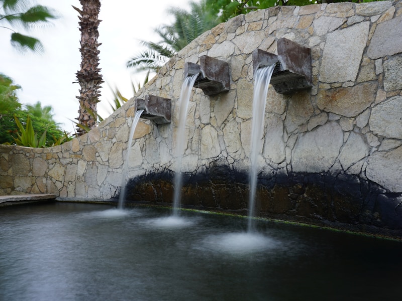 Stone water feature with three cascading spouts at twilight