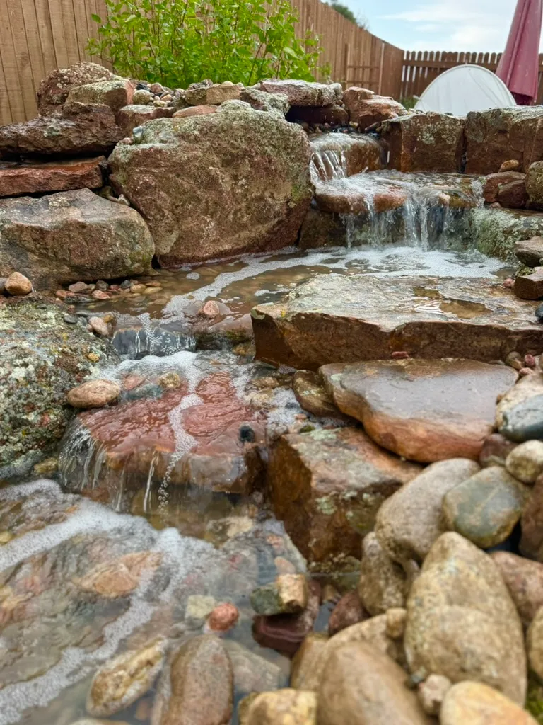 Pondless recirculating waterfall stream over natural stone with no open pond — custom waterfall builder Florida